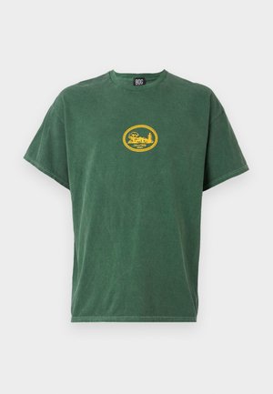 T-shirt en coton vert avec un col rond et des manches courtes. Présente un motif graphique circulaire jaune sur la poitrine. Texture douce.
