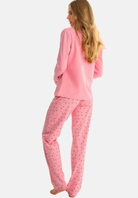 Haut à manches longues rose et pantalon de pyjama avec des motifs d'oiseaux colorés. Tissu doux, coupe décontractée et droite avec une taille élastique.