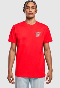 Camiseta corta roja de manga corta hecha de algodón, con un texto gráfico gris "KEEP IT 100%" en el área del pecho izquierdo, diseño estándar de cuello redondo.