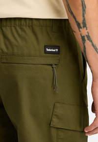 Olivově zelené cargo šortky z texturované tkaniny, s elastickým páskem, kapsou na zip a nášivkou Timberland na zadní straně.