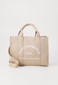 Beige lærred tote taske med to top håndtag og en aftagelig skulderrem. Har hvidt brandingskrift på forsiden. Struktureret design.