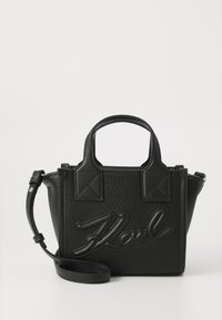 Sac à main en cuir noir avec une texture grainée, de courtes poignées doubles, une bandoulière amovible et un logo en relief à l'avant.