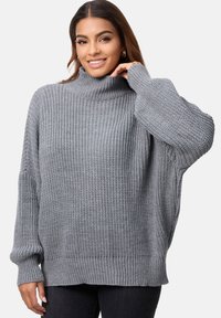 Przesadnie duży szary sweter z golfem, wykonany z fakturowanej dzianiny, z długimi rękawami i ściśniętym dołem. Minimalistyczny design, bez wzorów.