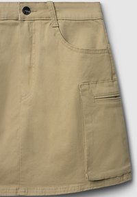 Gonna in cotone beige con tasca frontale, tasca cargo laterale e cuciture a vista. Vita piatta con chiusura a bottone.