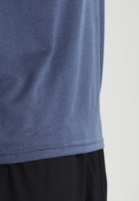 Kortärmad blå Dri-FIT tränings t-shirt med en mjuk textur, subtil melerad mönster och svart Dri-FIT-logotyp vid nederkanten.