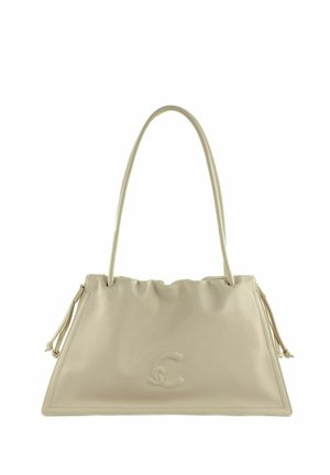 Sac à main en cuir beige avec une bandoulière unique, logo discret embossé et détails de pompons sur les côtés, forme trapézoïdale.