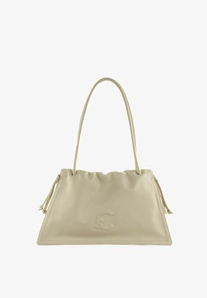Bolso de mano de cuero beige con una sola correa para el hombro, logo sutil en relieve y detalles de borlas laterales, forma trapezoidal.