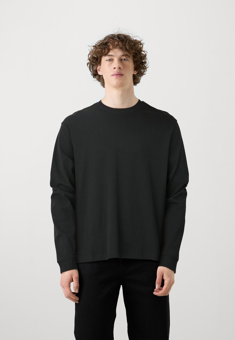 Zwarte lange mouwen T-shirt met ronde hals, gemaakt van katoen. Heeft een relaxed fit en een rechte zoom, met een eenvoudig, effen kleurontwerp.