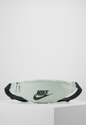 Banane Nike vert clair avec sangle noire réglable et fermeture éclair, avec logo Nike noir sur le devant.