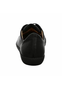 Black leather shoe with a rounded toe and slightly raised heel. Smooth texture, minimalist design, with a tan inner lining and black sole.