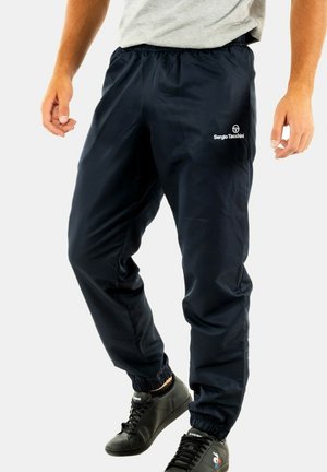 Navyblaue Trainingshose mit elastischem Bund und Bündchen, mit einem Logo am linken Oberschenkel. Hergestellt aus leichtem, glattem Material.