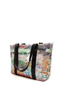 Multicolore tote bag met een gestructureerde stof met graffiti-achtige patronen in groen, zwart, oranje en paars. Zwarte handvatten om te dragen.