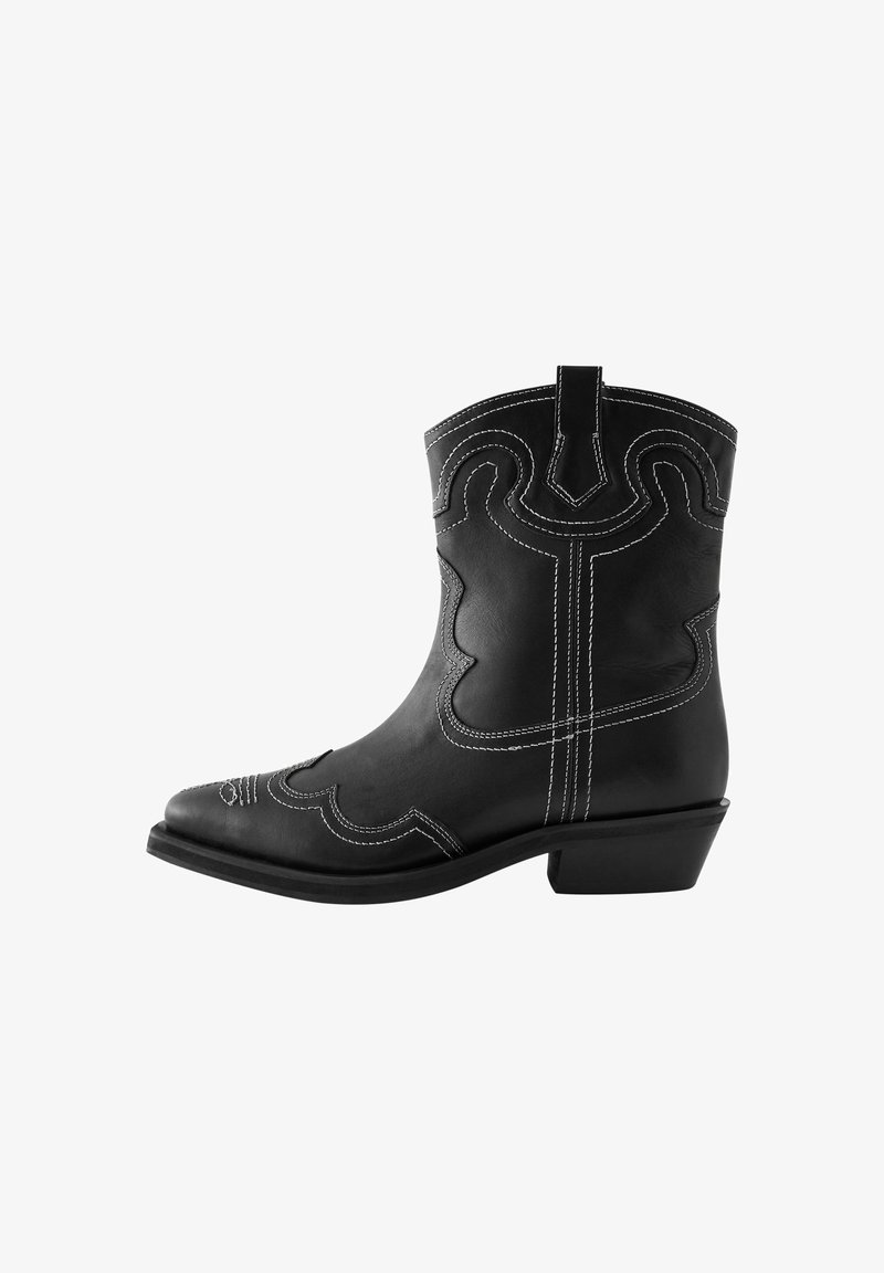 Fekete bőrcowboy csizma fehér varrással, hegyes orral és díszes hullámmintákkal. Alacsony sarokkal és húzófüllel rendelkezik.