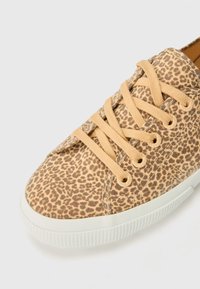 Leopard print sneaker with a tan fabric upper, beige laces, and a white rubber sole featuring a textured grip.