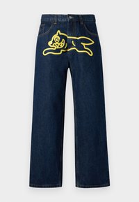 Dark blue denim jeans featuring a large yellow graphic of a leaping character on the back pocket. Straight leg design with standard stitching.