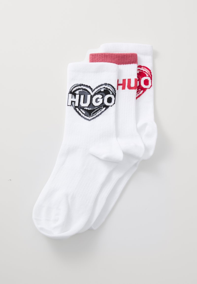 Hvide sokker med et sort og rødt hjerte-design og ordet "HUGO" i fed skrift. Blødt stof med ribbede bærestykker.