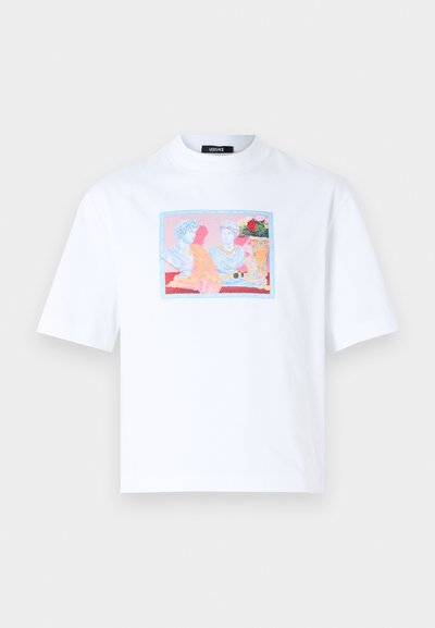 Valkoinen puuvillainen T-paita, jossa on värikäs painettu kuva klassisista hahmoista suorakulmaisessa kehyksessä edessä. Lyhyt hiha ja rento istuvuus.