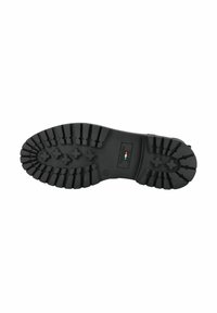 Suola di stivale in gomma nera con profonde scanalature, caratterizzata da una toppa logo rettangolare. Il design include vari schemi di aderenza per presa e stabilità.