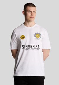 Weißes Baumwoll-T-Shirt mit runden Logos und gelben Akzenten, "SUNNIES E.F." in fettem schwarzen Text und einem floralen Grafikdesign. Kurzärmlig.