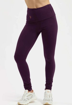 Leggings violettes avec une taille haute, fabriquées à partir d'un matériau extensible. Présentent des détails froncés aux chevilles et un logo contrastant à la taille.