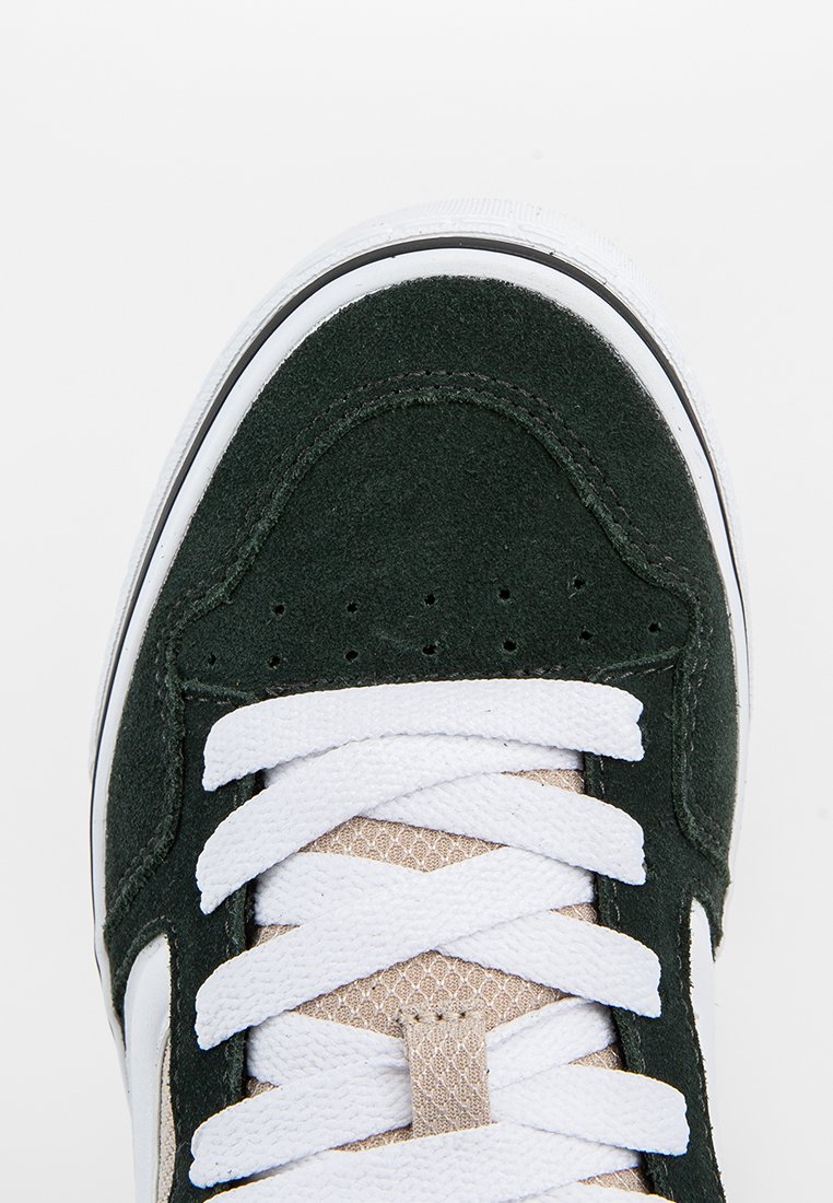 Bout de sneaker noir et blanc avec des lacets blancs et une languette en mesh beige, vue du dessus sur un fond blanc uni.
