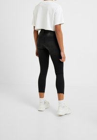 Höga svarta skinny jeans med fransade fållar och en smal passform, i kombination med en kort vit t-shirt och vita sneakers.