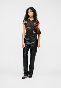 Μαύρο φλοράλ t-shirt με κοντά μανίκια, συνδυασμένο με κομψό μαύρο δερμάτινο παντελόνι. Συμπληρωμένο με μικρή μπορντό τσάντα και μυτερές γόβες.