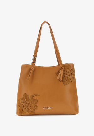Brązowa skórzana torba typu tote z dwoma paskami na ramię, kwiatowymi aplikacjami z zamszu na rogach oraz małą metalową plakietką z logo na przodzie.