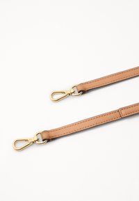 Curea din piele bej cu clipsuri din metal de culoare aurie la capete. Prezintă cusături de-a lungul marginilor. Textură netedă, design minimalist.