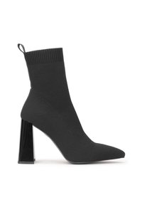 Black sock-style high heel boot with pointed toe and a transparent block heel. Features a ribbed top and smooth fabric texture.