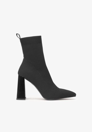 Black sock-style high heel boot with pointed toe and a transparent block heel. Features a ribbed top and smooth fabric texture.