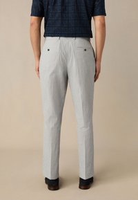 Pantalon gris clair à finition texturée et coupe droite, doté de deux poches arrière avec boutons foncés et de détails de couture minimalistes.