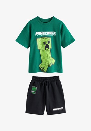 Grøn Minecraft T-shirt med stort Creeper-grafik og sorte shorts med Minecraft-logo og Creeper-patch.