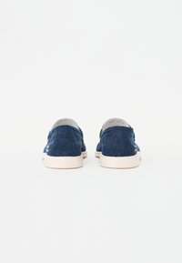 Blauwe denim instappers met een textuurstof, witte rubberen zolen en grijze accenten bij de hak, ontworpen voor casual gebruik.
