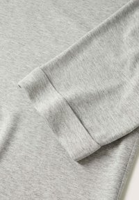 Manchette en tissu gris clair avec un revers plié, montrant une texture douce et lisse ainsi que des fines coutures.