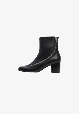 Musthave must tume kummikud terava nina ja külgmise lukuga, millel on virnastatud puidust konts. Sile tekstuur ja šikk disain.