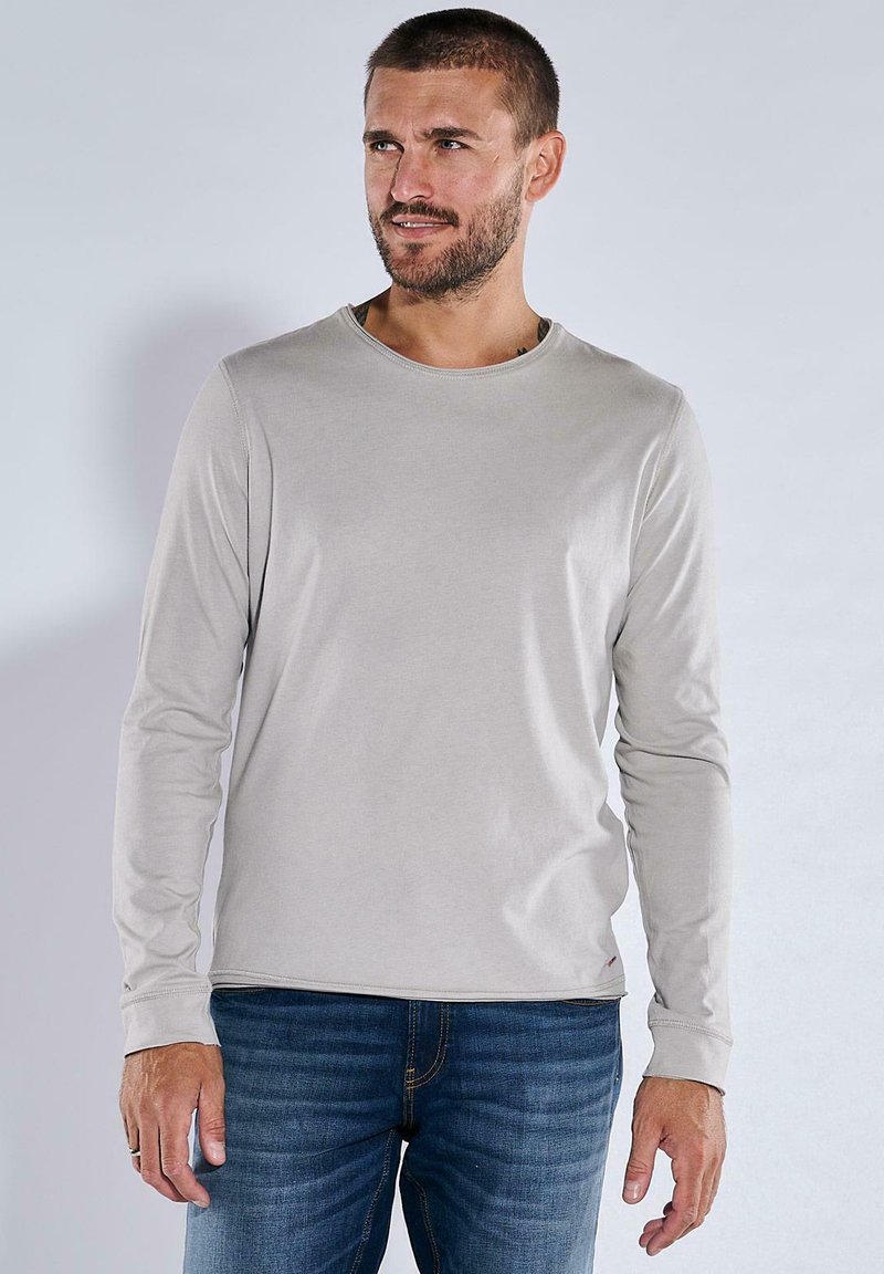 Hellgraues Langarm-T-Shirt mit rundem Ausschnitt, aus weichem Stoff, getragen mit blauen Jeans, mit einer einfachen und glatten Textur.