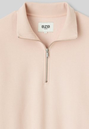 Pull-over rose clair, surdimensionné, avec un demi-zip. Tissu doux avec un col côtelé, comportant une fermeture éclair argentée et une étiquette affichant "BZB."