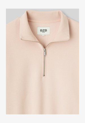 Pull-over rose clair, surdimensionné, avec un demi-zip. Tissu doux avec un col côtelé, comportant une fermeture éclair argentée et une étiquette affichant "BZB."