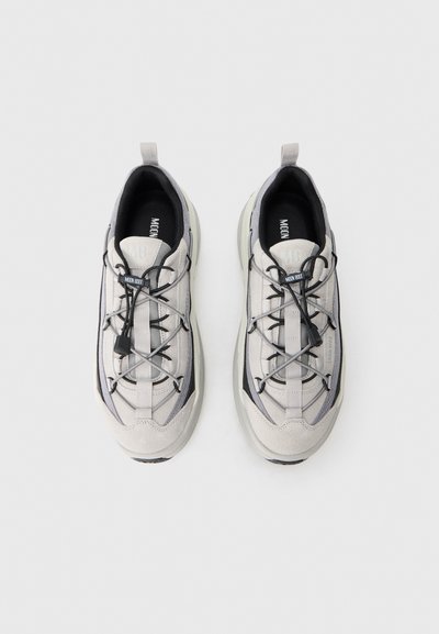Zapatillas deportivas grises y beige con una combinación de ante y malla, que cuentan con cordones elásticos, cuello acolchado y suelas de goma.