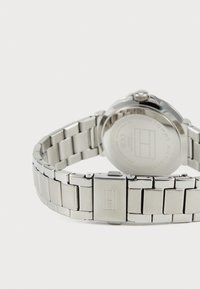 Stainless steel wristwatch with a metal band, round case, and visible back. Features a prominent logo and polished finish.