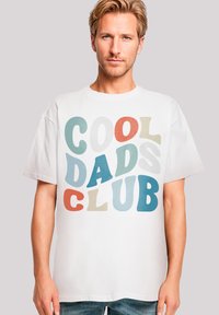 White cotton t-shirt featuring multicolored, bold text reading "COOL DADS CLUB" in varying styles and sizes. Short sleeves, casual fit.