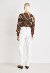 Suéter de estampado de leopardo marrón y beige combinado con pantalones vaqueros de pierna ancha blancos. Textura suave, mangas acanaladas y ajuste de cintura alta. Calzado marrón.