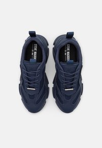 Navy blue sneakers featuring a mesh upper, textured panels, prominent laces, and a logo tag on the tongue. Rubber sole with distinct tread.