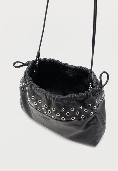 Μαύρη δερμάτινη τσάντα ώμου με κορδόνι στο πάνω μέρος, διακοσμητικά από ασημένιες τρύπες και λεπτό λουρί. Το εσωτερικό είναι ανοιχτό και ευρύχωρο.
