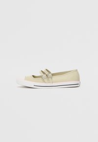 Zapatos slip-on de color verde claro con correas de doble hebilla, puntera de goma blanca y suela con borde rosa, que presentan una textura suave y una forma redondeada.