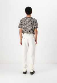 Zwart-wit gestreepte t-shirt met korte mouwen, gecombineerd met witte broek. De outfit heeft een relaxed fit en een zachte stofstructuur.