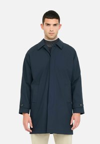 Impermeabile blu navy con collo a righe, chiusura frontale con bottoni, tasche laterali e dettagli a coste sul colletto interno.