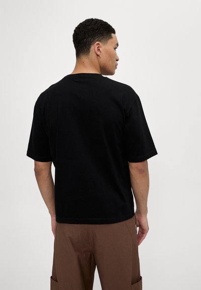 Sort bomulds t-shirt med korte ærmer, rund hals og en afslappet pasform. Bagsiden er ensfarvet og viser en glat tekstur og rene sømme.