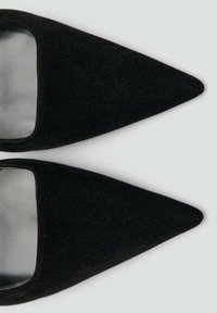 Svarta sammetspointade flats med ett utskärningsmönster, slät inredning och utan synlig hårdvara eller utsmyckningar.